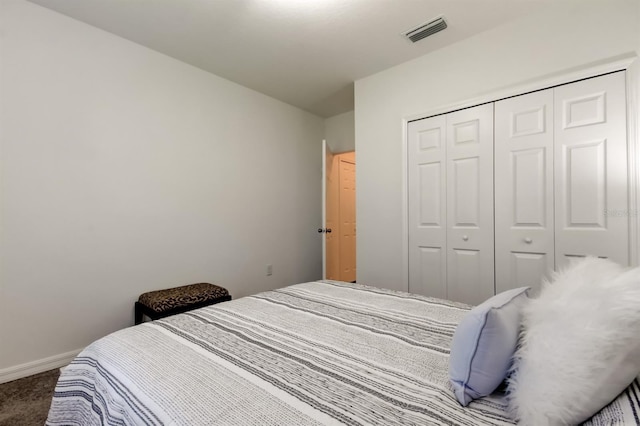carpeted bedroom with visible vents, baseboards, and a closet