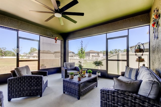 sunroom featuring a residential view, ceiling fan, and an outdoor living space