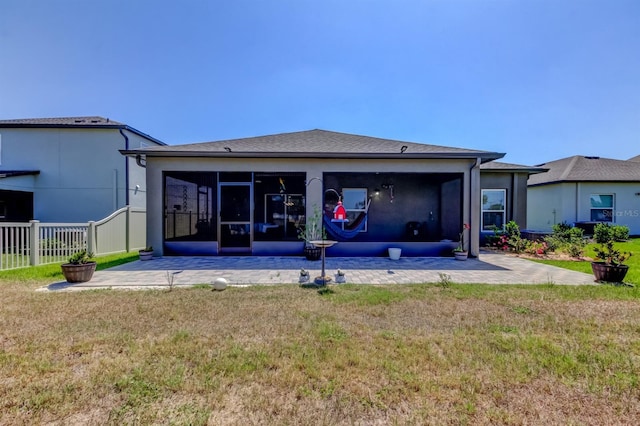 back of property with a sunroom, stucco siding, fence, and a yard