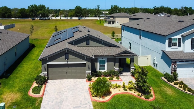 craftsman inspired home featuring decorative driveway, roof mounted solar panels, stucco siding, and a front yard