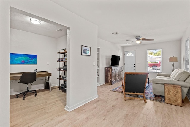 living room featuring baseboards, light wood finished floors, ceiling fan, and visible vents