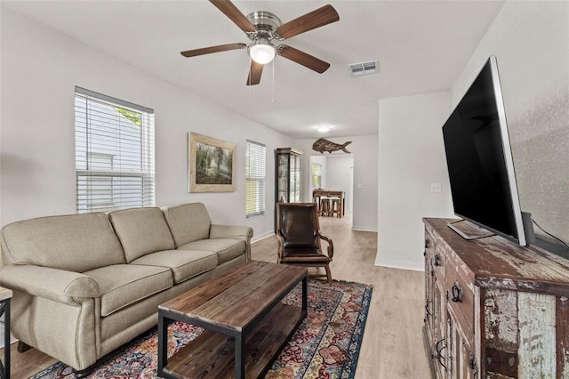 living room featuring baseboards, ceiling fan, light wood-style flooring, and visible vents
