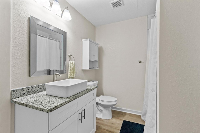 full bathroom featuring visible vents, wood finished floors, vanity, baseboards, and toilet