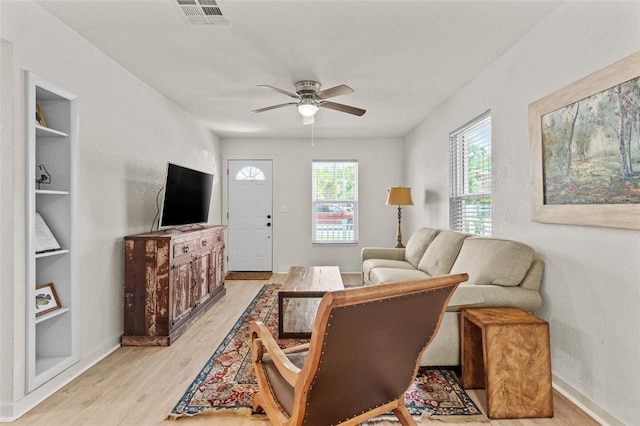 living area featuring visible vents, light wood-style flooring, ceiling fan, and built in features
