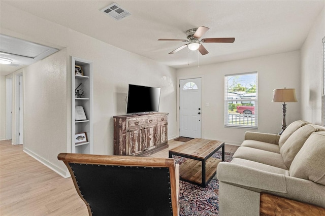 living area featuring baseboards, ceiling fan, light wood-type flooring, and visible vents