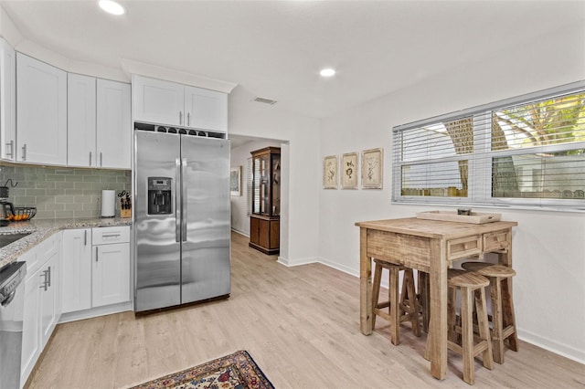 kitchen with visible vents, baseboards, light wood-type flooring, white cabinetry, and appliances with stainless steel finishes