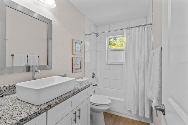 full bath with vanity, wood finished floors, shower / bath combo, and toilet