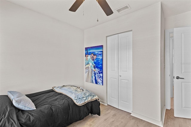 bedroom with light wood-style flooring, a ceiling fan, baseboards, visible vents, and a closet