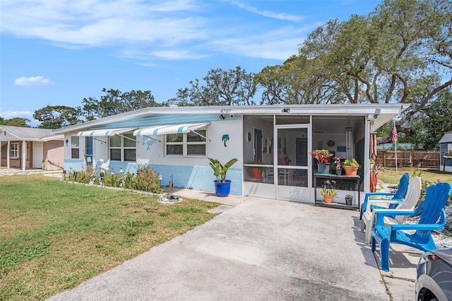back of house featuring a lawn, fence, and a sunroom