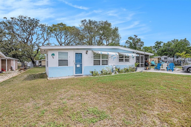 manufactured / mobile home with a sunroom, concrete block siding, fence, and a front yard