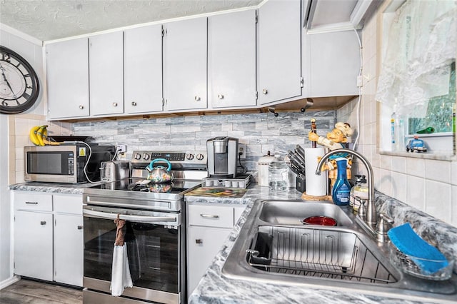 kitchen featuring crown molding, decorative backsplash, light countertops, a sink, and appliances with stainless steel finishes