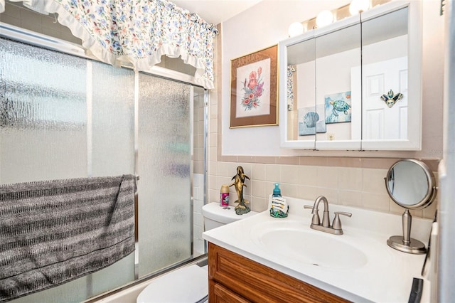 bathroom featuring vanity, toilet, tile walls, tasteful backsplash, and bath / shower combo with glass door