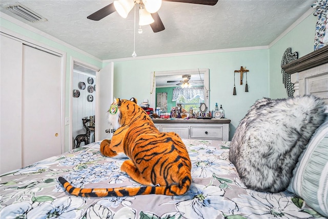 bedroom with visible vents, ornamental molding, a closet, a textured ceiling, and a ceiling fan