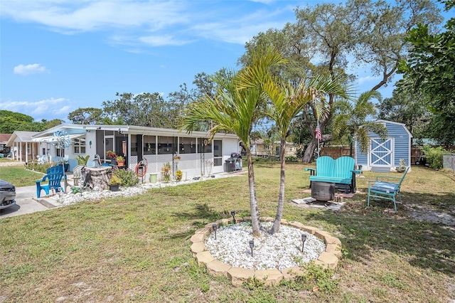 view of yard featuring a sunroom, fence, an outdoor structure, a shed, and a fire pit