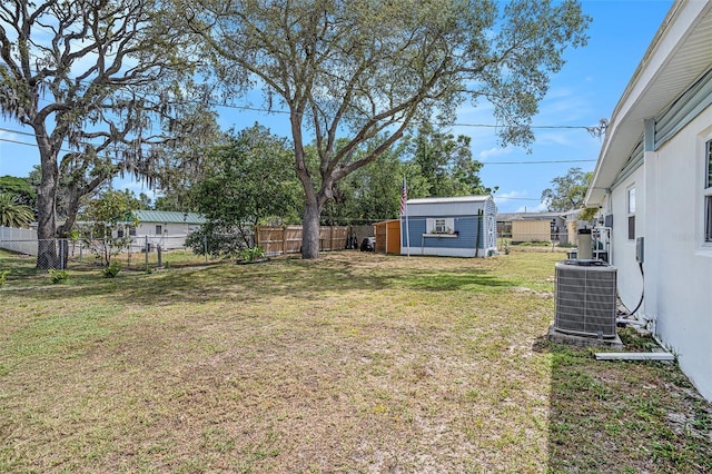 view of yard featuring an outdoor structure, cooling unit, a fenced backyard, and a shed