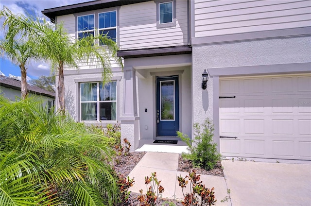entrance to property with a garage and stucco siding