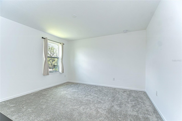 carpeted empty room featuring baseboards