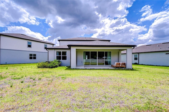 back of property with a patio, stucco siding, and a yard