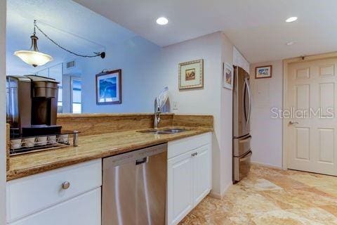 kitchen featuring white cabinetry, light stone countertops, appliances with stainless steel finishes, and a sink