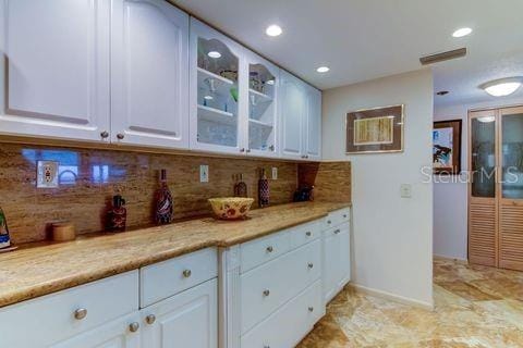 kitchen with white cabinets, backsplash, and glass insert cabinets
