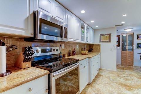 kitchen with light countertops, appliances with stainless steel finishes, white cabinets, and decorative backsplash
