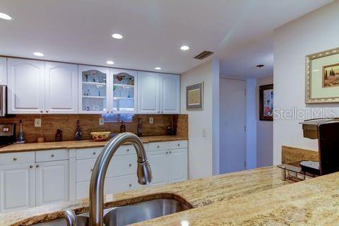 kitchen with light stone countertops, white cabinetry, and visible vents