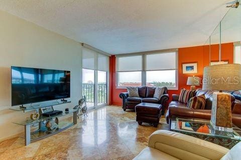 living area featuring a wall of windows, plenty of natural light, and a textured ceiling