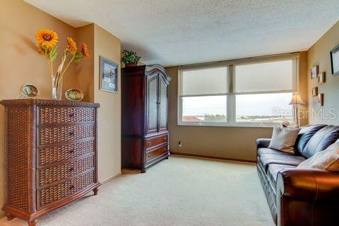 interior space with a textured ceiling, light colored carpet, and baseboards
