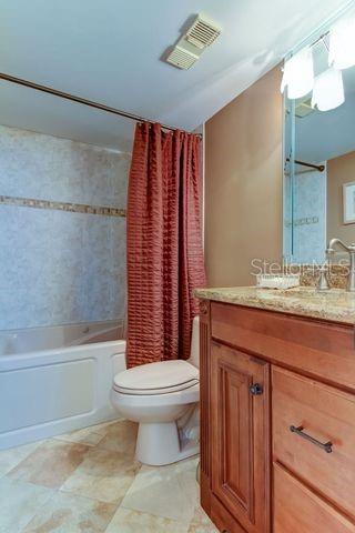 full bath featuring shower / tub combo with curtain, vanity, toilet, and visible vents