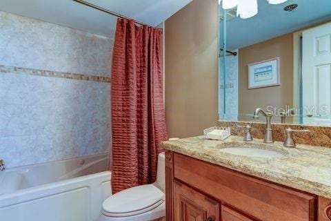 bathroom featuring vanity, toilet, and shower / tub combo with curtain