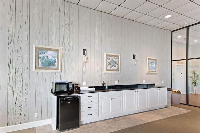 kitchen featuring black microwave, dark countertops, fridge, a sink, and baseboards