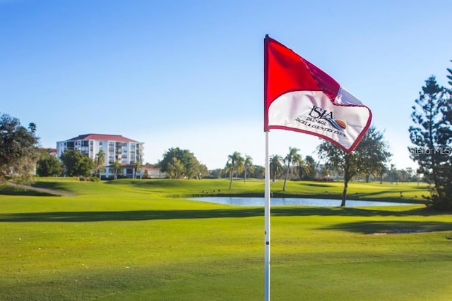 view of home's community featuring a lawn, a water view, and view of golf course