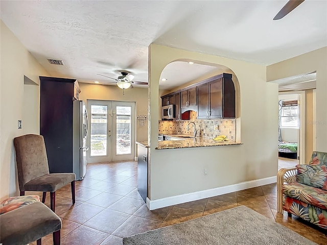 10931 110th Ave, Seminole, FL 33778 - kitchen with ceiling fan, stainless steel appliances, light stone countertops, decorative backsplash, and dark brown cabinetry