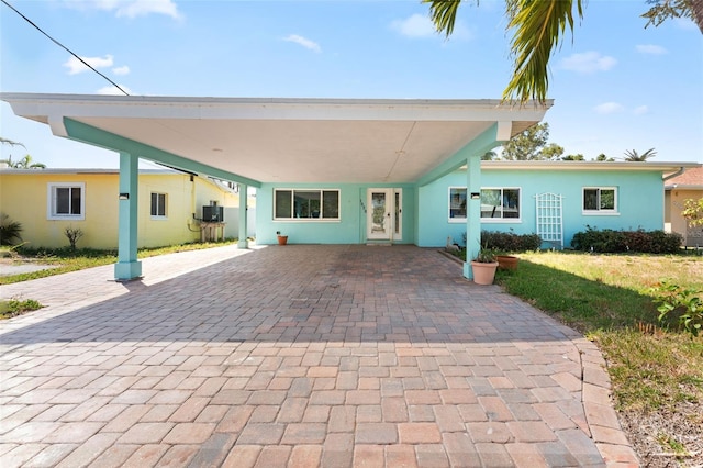 1025 Boca Ciega Isle Dr, St Pete Beach, FL 33706 - exterior space featuring decorative driveway, stucco siding, a front yard, and a carport