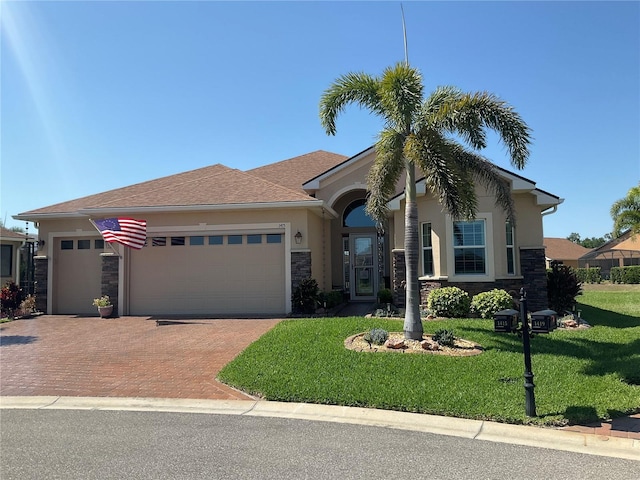 view of front of property with decorative driveway, a front lawn, stone siding, and a garage