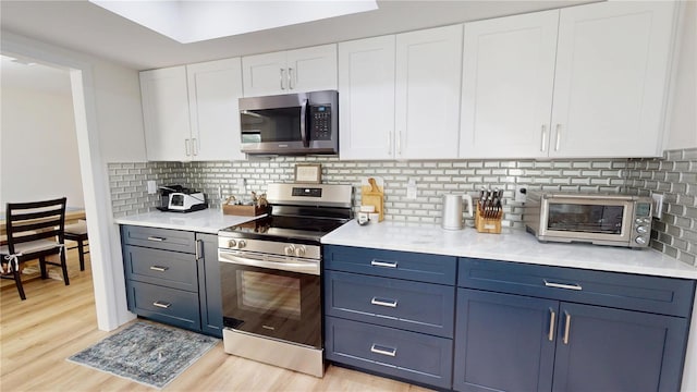 1849 Del Robles Dr, Clearwater, FL 33764 - kitchen with decorative backsplash, appliances with stainless steel finishes, light countertops, light wood-style floors, and white cabinetry