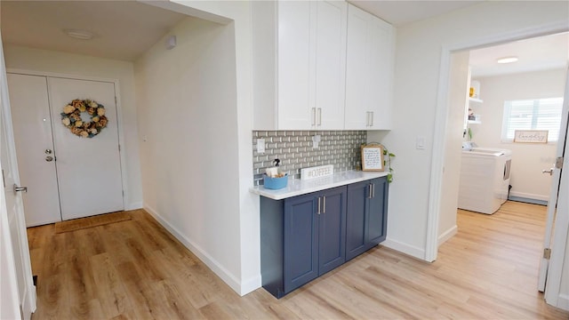1849 Del Robles Dr, Clearwater, FL 33764 - kitchen with washing machine and clothes dryer, tasteful backsplash, light wood-style flooring, light countertops, and white cabinetry