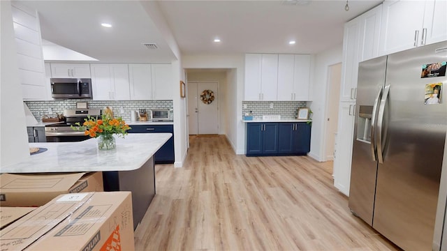 1849 Del Robles Dr, Clearwater, FL 33764 - kitchen with decorative backsplash, light wood-type flooring, light countertops, white cabinetry, and stainless steel appliances