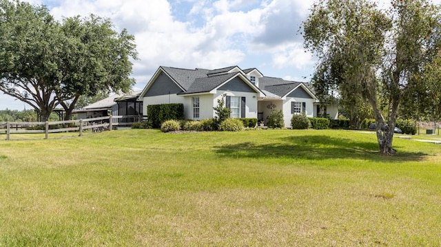 view of front facade with fence, roof with shingles, stucco siding, and a front lawn