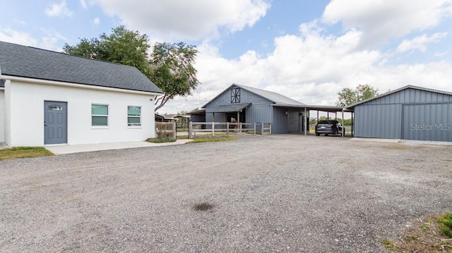 view of front of home featuring fence, driveway, an outdoor structure, and an attached carport
