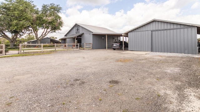view of pole building featuring fence and gravel driveway
