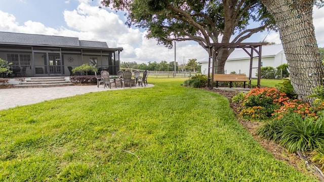 view of yard featuring a patio, fence, a sunroom, and an outdoor fire pit