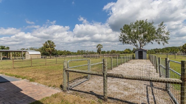 view of yard with an outdoor structure, a gate, fence, and a rural view