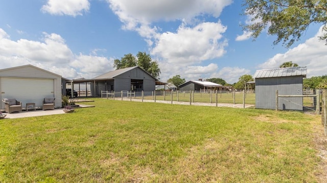 view of yard with a pole building, fence, and an outbuilding