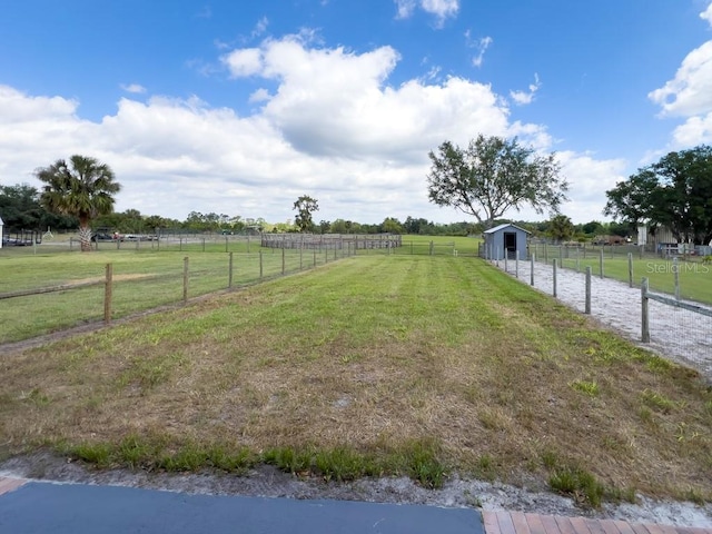 view of yard featuring fence, an outbuilding, and a rural view