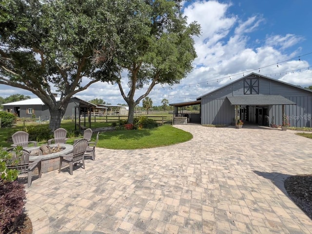 view of patio / terrace featuring decorative driveway, a fire pit, an outdoor structure, and a carport