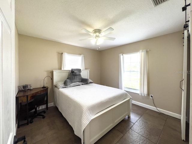 bedroom with baseboards, a ceiling fan, a barn door, and multiple windows