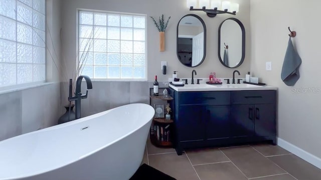 full bathroom featuring plenty of natural light, a sink, double vanity, and a soaking tub