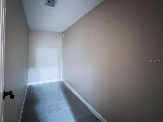 interior space with baseboards, dark tile patterned floors, and visible vents