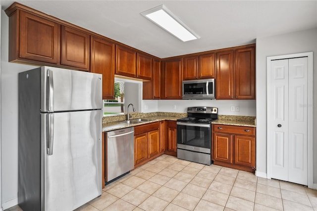 1506 Lenton Rose Ct, Trinity, FL 34655 - kitchen featuring brown cabinets, light stone countertops, appliances with stainless steel finishes, a sink, and light tile patterned floors